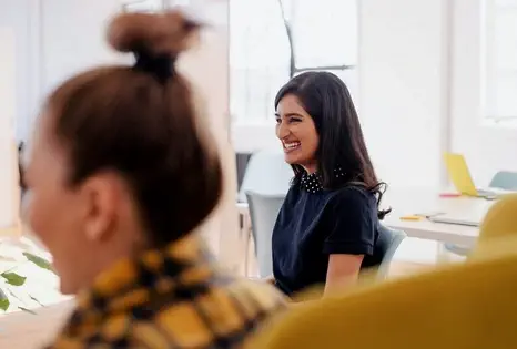 Au deuxième plan, une femme assise, le regard porté vers la gauche et souriante.