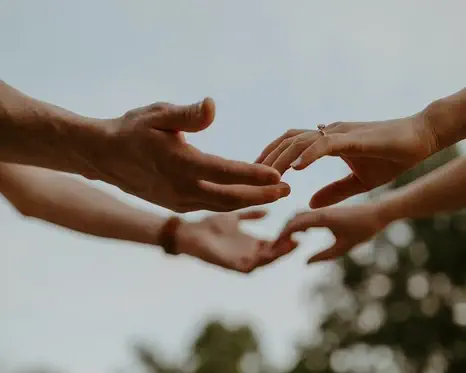 Gros-plan sur les mains de deux personnes, s'effleurant les doigts.